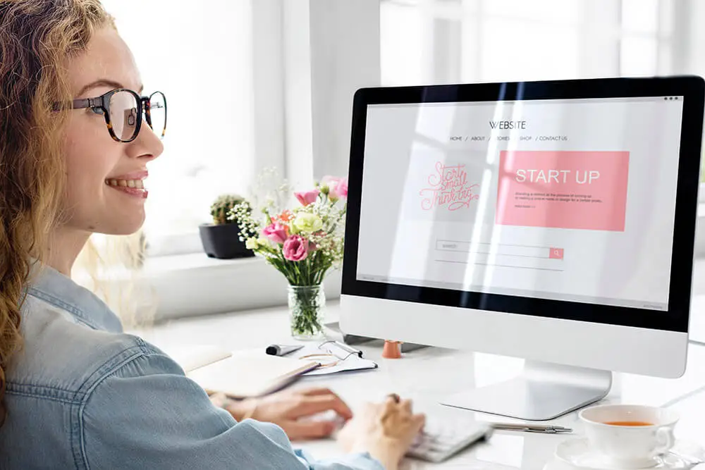 3º local em que seu negócio precisa estar para uma boa presença digital - Local de credibilidade e venda direta - Moça sorrindo e digitando no teclado de um computador com seu site / website aberto.